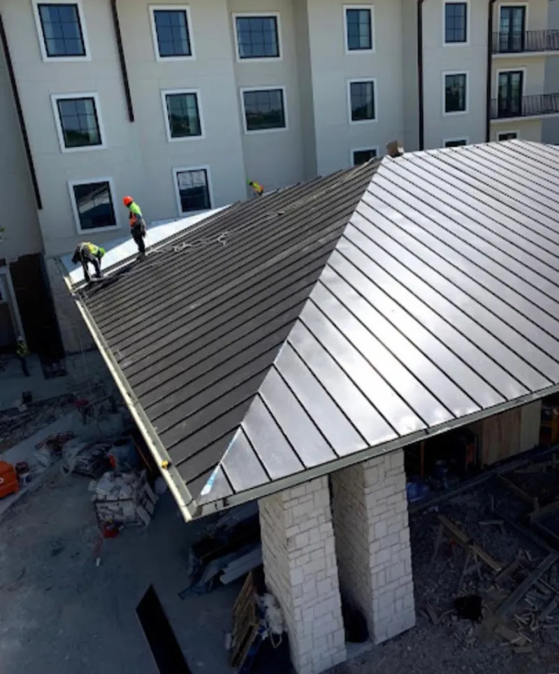Crew installing standing seam metal roof panels on a commercial project in Pleasant Hills